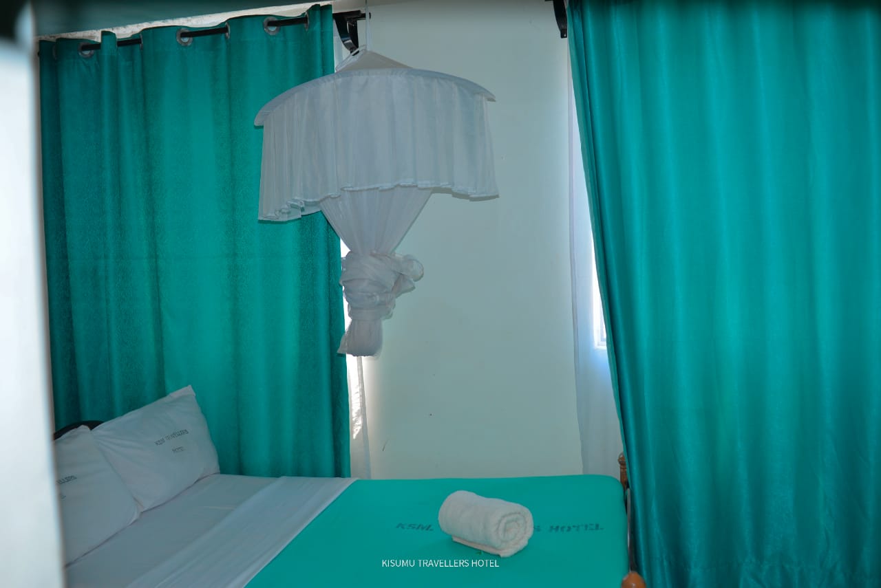 Standard self-contained room with private bathroom, turquoise bedding and mosquito net