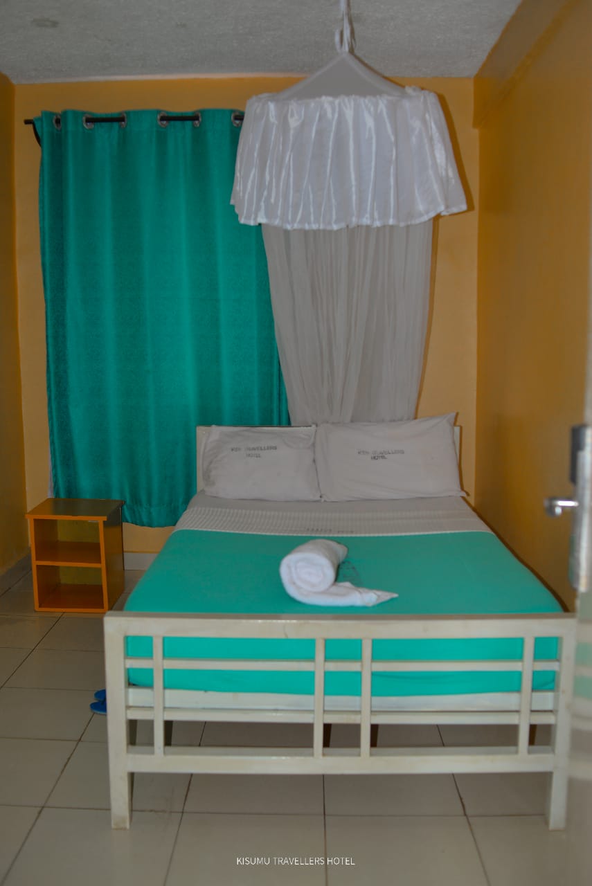 Double standard room with large white bed frame and turquoise bedding